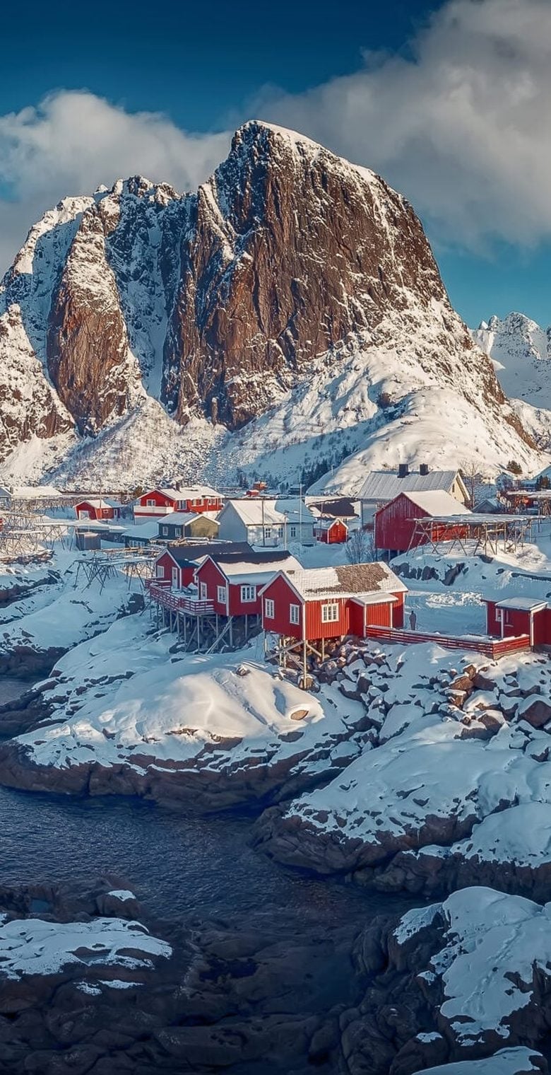 Red fishing cabins below a mountain peak in the Lofoten Islands